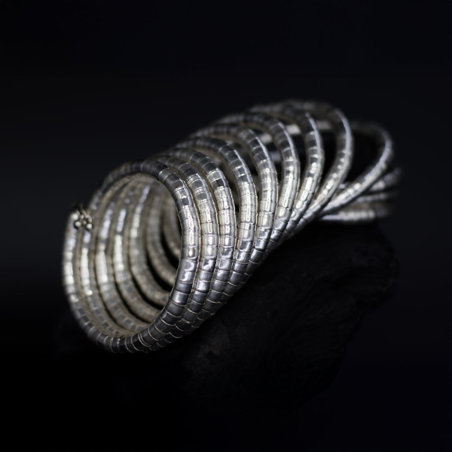 DIVAMAS Silver coil-style spring bangles stacked in side view, contemporary jewelry design for women._02