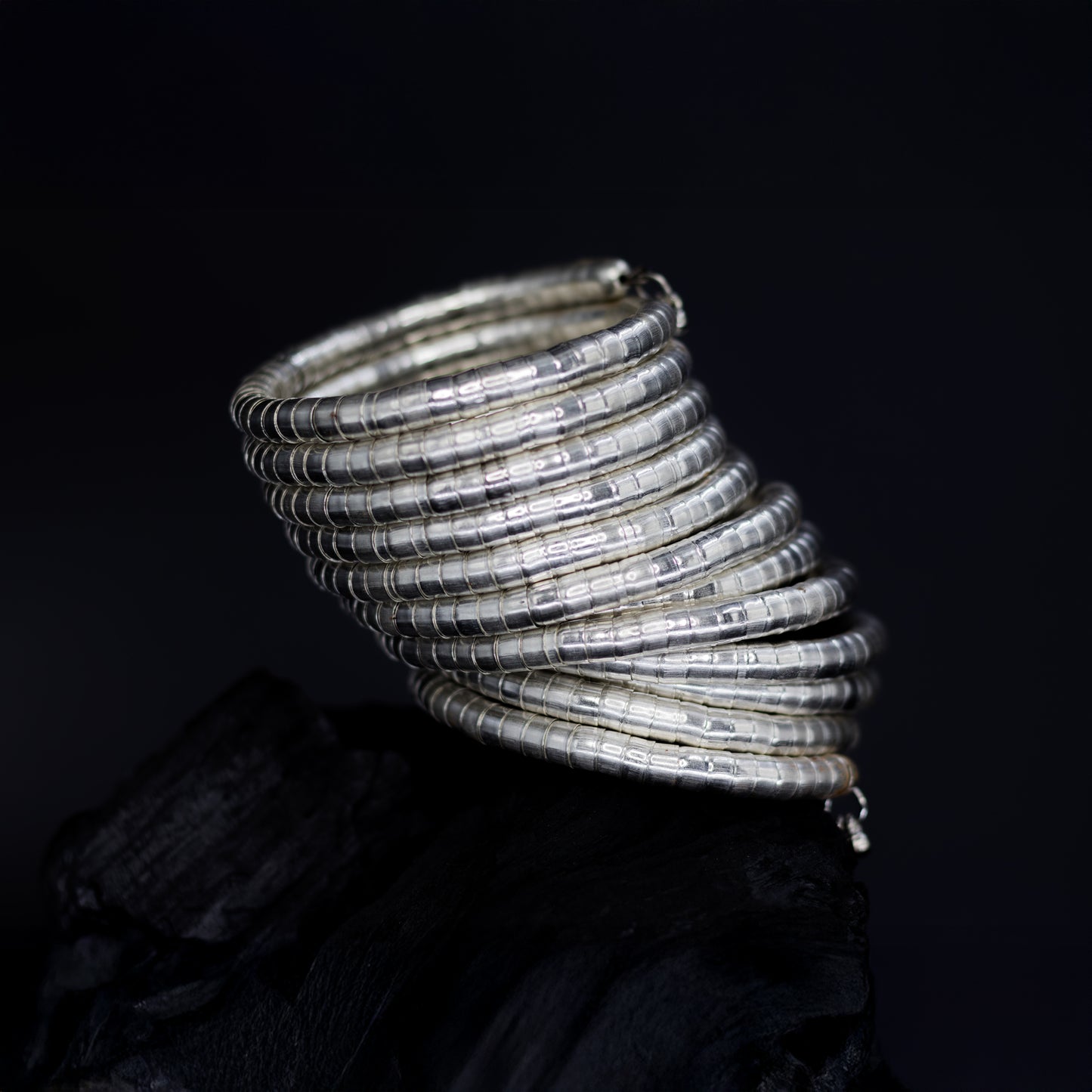 DIVAMAS Silver coil-style spring bangles stacked in side view, contemporary jewelry design for women._01