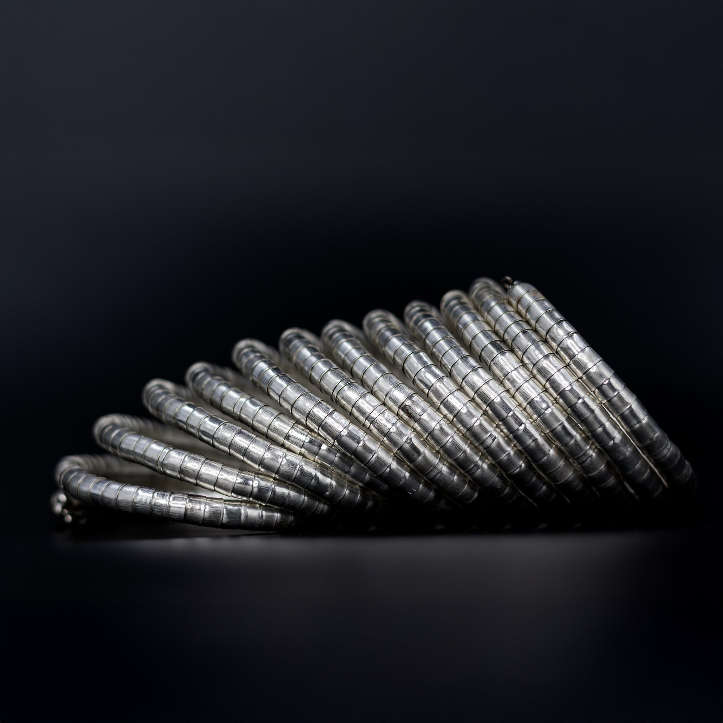 DIVAMAS Silver coil-style spring bangles stacked in side view, contemporary jewelry design for women._03