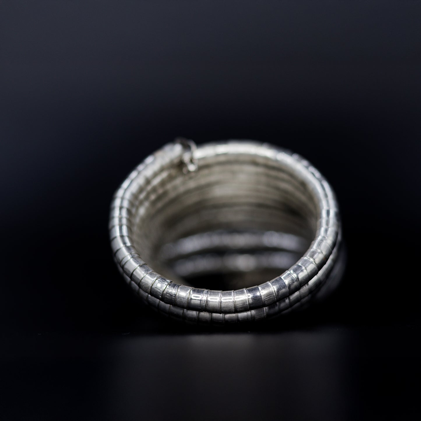 DIVAMAS Silver coil-style spring bangles stacked in side view, contemporary jewelry design for women._04