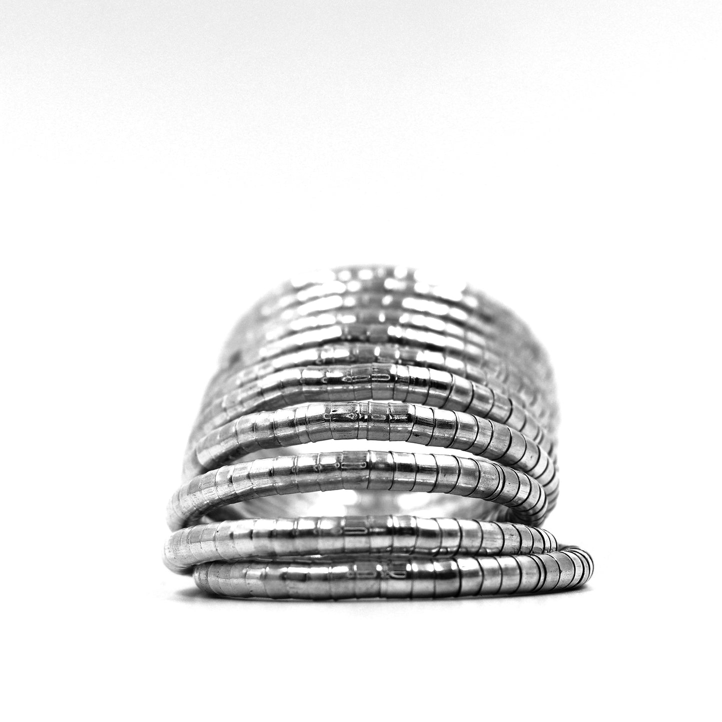DIVAMAS Silver coil-style spring bangles stacked in side view, contemporary jewelry design for women._06