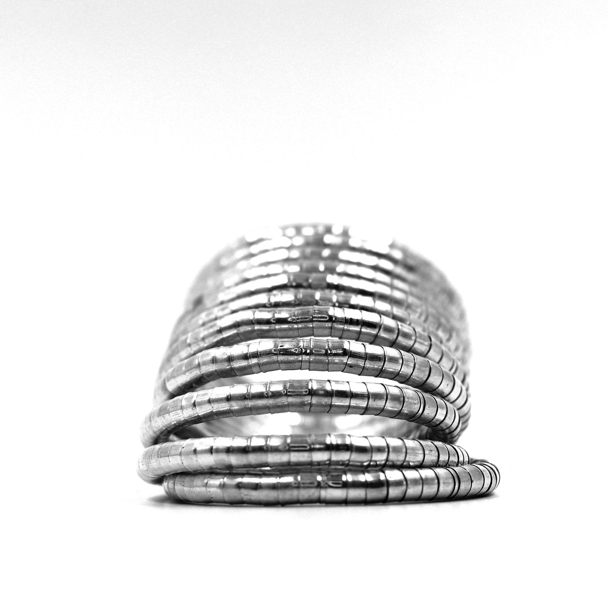 DIVAMAS Silver coil-style spring bangles stacked in side view, contemporary jewelry design for women._06