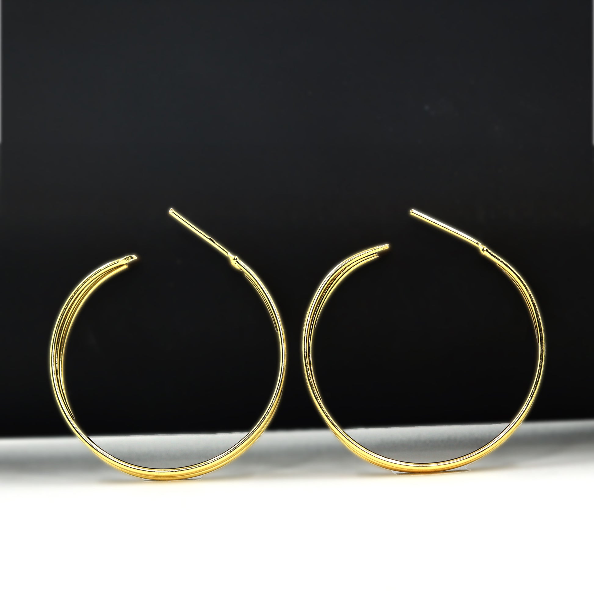 Gold hoop earrings with a sleek, polished finish from DIVAMAS displayed on a white background_04



