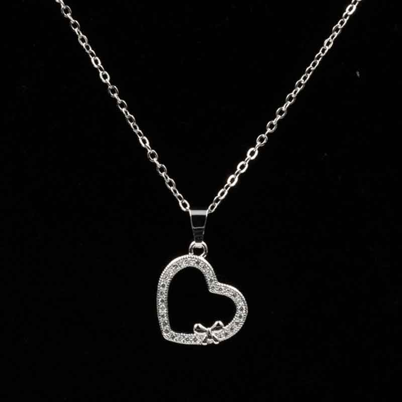 Elegant gold and silver heart pendant necklace featuring an open heart design with sparkling stones and a delicate bow accent, perfect for special occasions and everyday wear.